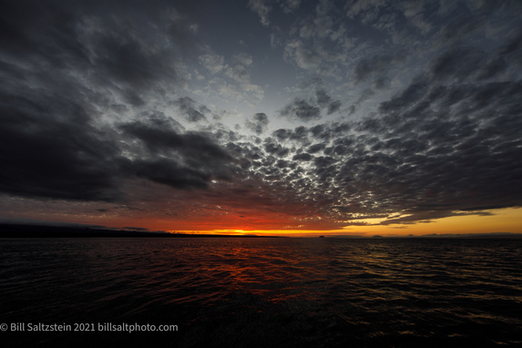 dramatic sunset in the Galapagos Islands, with a bright orange band of light sandwiched between the dark sea and a partly cloudy sky