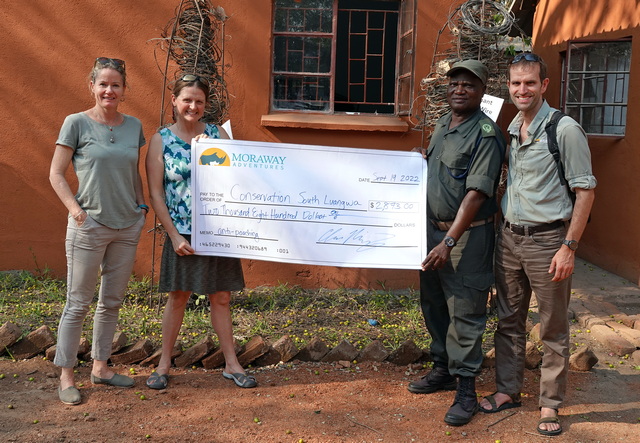 safari guests present a donation check to Conservation South Luangwa