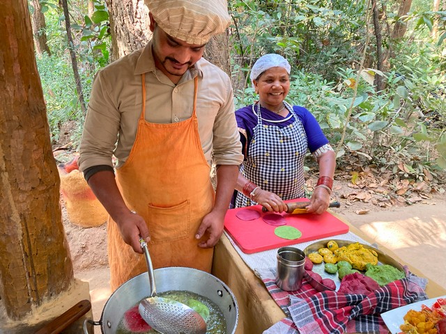 The chef and assistant at Kanha Jungle Lodge smile cheerfully as they cook homemade food for guests on a luxury tiger safari in India