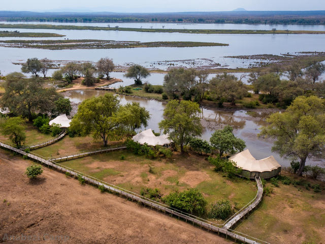 Aerial shot of three luxurious safari tents along the river at Anabezi Camp, a luxury safari camp in the Lower Zambezi of Zambia