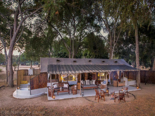 Open air dining area and fire pit under the trees at Old Mondoro Camp, a luxury safari camp in the Lower Zambezi, Zambia