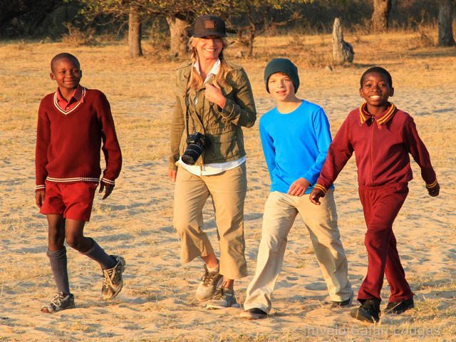 A mother and her son walk to school with two local children during a village visit on a luxury safari at Camelthorn Lodge in Hwange National Park
