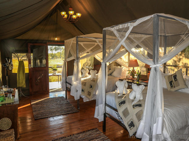 Two canopied beds in a beautifully decorated safari tent at Nehimba Camp, a luxury safari camp in Hwange National Park Zimbabwe