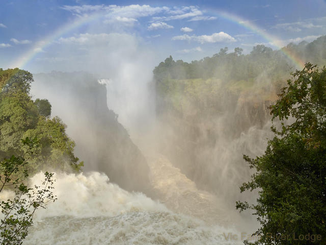 The rushing waters of Victoria Fall, with a rainbow framing the mist and the falls