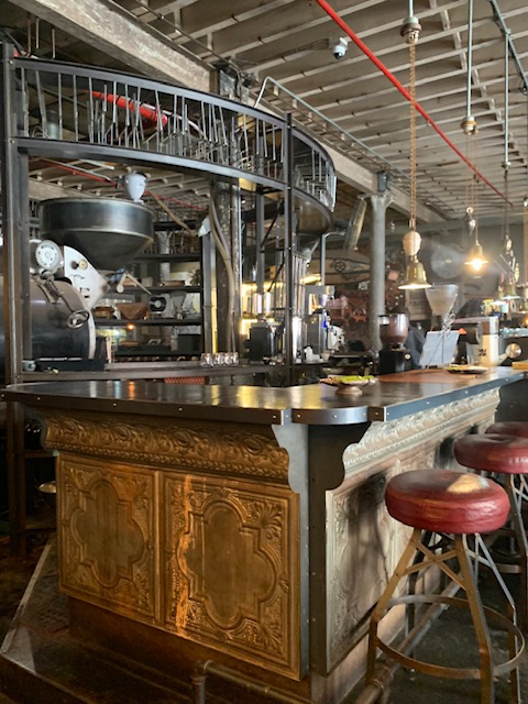 interior of a coffee shop in Cape Town, with stools at a car and coffee equipment in the background