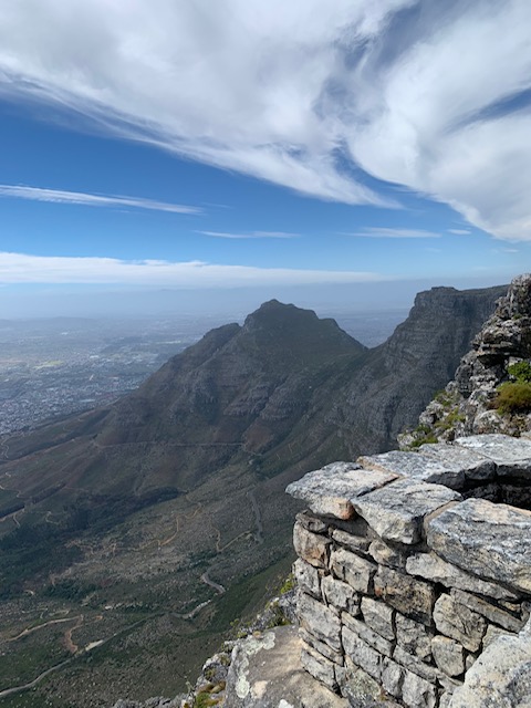 Landscape view looking down from Table Mountain in Cape Town, with the city sprawling beneath a partly cloudy sky