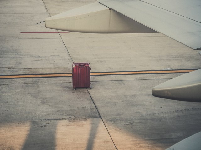 suitcase sitting on the tarmac next to a jumbo jet