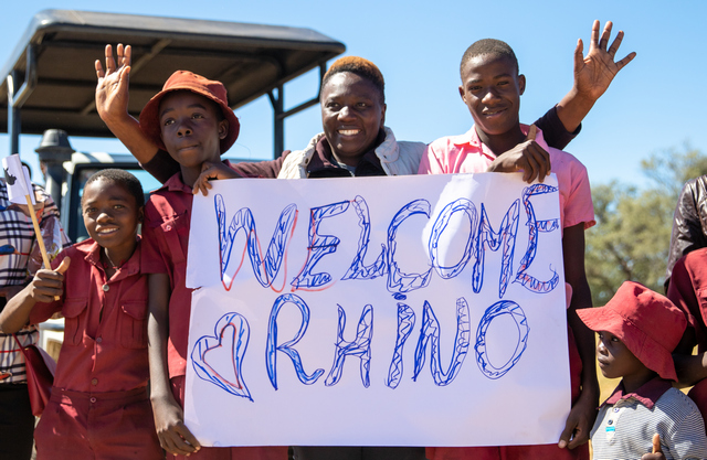 Villagers who live adjacent to Hwange National Park hold up a "welcome rhino" sign