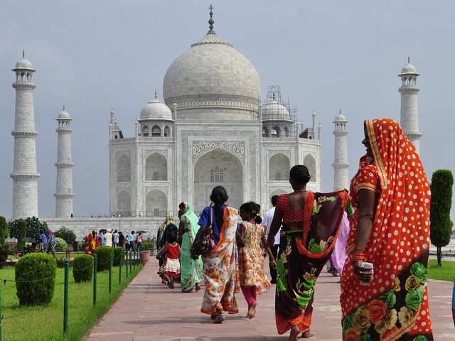 Women in colorful saris walk toward the Taj Mahal in India