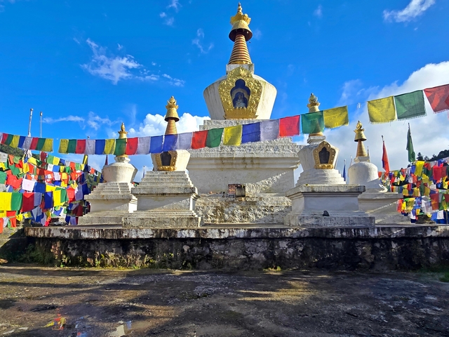 A gold-capped stupa flanked by smaller stupas and fluttering prayer flags at Gangtey pass Bhutan
