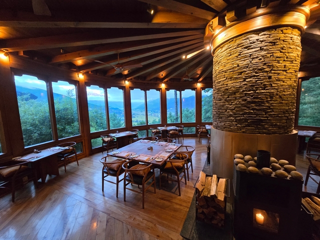 Looking across the dining room of Como Uma Paro hotel in Bhutan, with lush green landscapes of the Paro Valley visible out the windows
