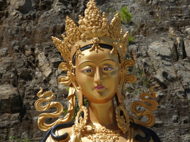 Portrait of the face of a golden Dakini statue, with elaborate crown.
